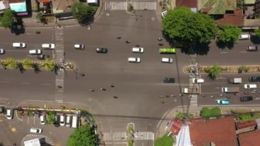 Şehir trafiği kavşağında güneşli bir gün olan Bali Adası uçuşu, gökyüzü tepeden aşağı panorama, 4K Endonezya