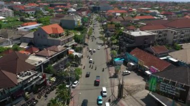 Şehir trafiği kavşağında güneşli bir gün olan Bali Adası uçuşu, gökyüzü tepeden aşağı panorama, 4K Endonezya