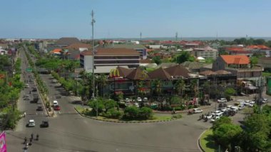 Şehir trafiği kavşağında güneşli bir gün olan Bali Adası uçuşu, gökyüzü tepeden aşağı panorama, 4K Endonezya