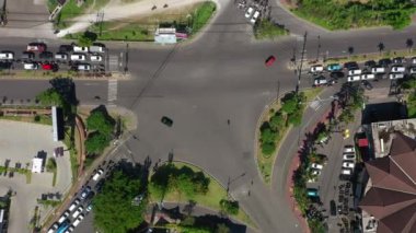 Şehir trafiği kavşağında güneşli bir gün olan Bali Adası uçuşu, gökyüzü tepeden aşağı panorama, 4K Endonezya