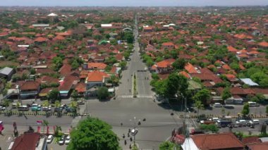 Şehir trafiği kavşağında güneşli bir gün olan Bali Adası uçuşu, gökyüzü tepeden aşağı panorama, 4K Endonezya