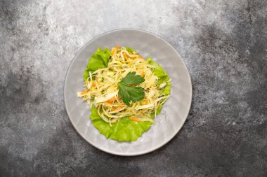 Gri tabakta lahana ve havuç salatası ve gri arka plan. Üst görünüm.