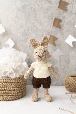 knitted hare with a knitted basket with threads and flags on the wall