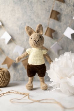 knitted hare with threads and flags on the wall