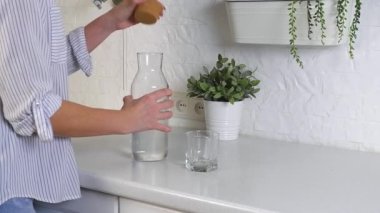 woman hands pouring water from a bottle into a glass