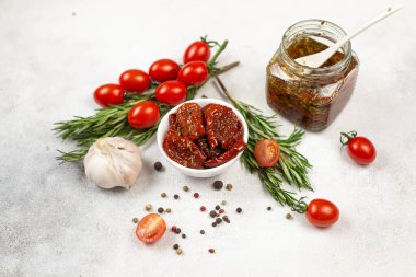 Taze bitkilerle, baharatlarla, domateslerle ve sarımsakla kurutulmuş domatesler. Gri arka plan. Üst görünüm.