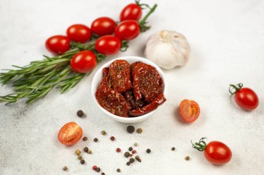 Taze bitkilerle, baharatlarla, domateslerle ve sarımsakla kurutulmuş domatesler. Gri arka plan. Üst görünüm.