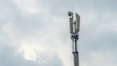 Gökyüzü arka planında mobil operatör antenleri olan kule. Kule ekipman selülasını barındırıyordu. Metin için boşluk.