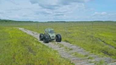 Alçak basınçlı tekerlekleri ve ulaşılması zor lastikleri olan özel bir off-road arabası. Her yere yayılmış bir araç. Dramatik gökyüzü arka planında bataklık için ekolojik taşıma.