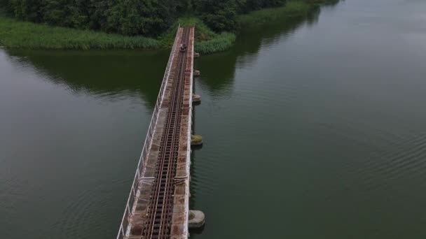 狭軌鉄道線と橋の空中トップダウンビュー 人々は水の上の鉄道トロリーに乗っています アドベンチャーコンセプト — ストック動画