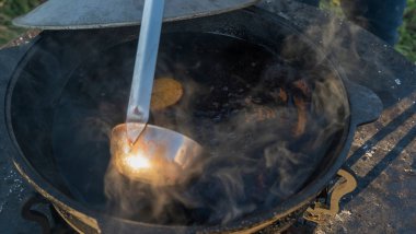 Sıcak sıcak şaraplı kazanlar. Sıcak şarap sokaktaki eski bir kazanda pişirilir. Açık ateşte yemek pişirmek. Yakın plan. Neşeli alkol içeceği..