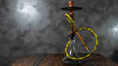 Yeni modern oryantal nargile. Gri arka plandaki ahşap masada duruyor..