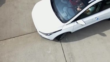 Test pistinde tur atan yeni bir elektrikli arabanın havadan görüntüsü. Geniş açıda elektrikli araba test sürüşü. Yeşil enerji kavramı.