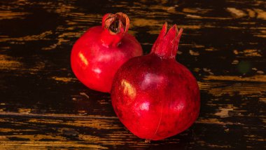 Masada iki kırmızı nar yatıyordu. Ahşap masada iki olgun taş. Tüylü yemek. Hayat konsepti.