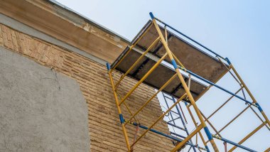 Eski bir binanın tadilatı. Evin duvarının yanında iskele var. Mesaj için yer var. Yeniden yapılanma kavramı.