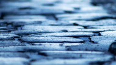 Kaldırımların yapısı eski granit kare elementlerden yapılmış. Seçici odaklanma. Perspektif doğrusal. Kadim kaldırım taşları dokusu ve arkaplanı. Tasarım için resim. Metin için boşluk.