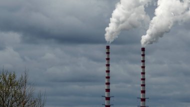 Gökyüzü arka planında bacadan çıkan endüstriyel duman. Kömür santralinden çıkan gri dumanlı yüksek baca borularının görüntüsü. Fosil yakıtlı elektrik üretimi. Rüzgâr kirliliği.