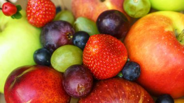 Yaz meyveleri, böğürtlen çeşitleri. Büyük elma, erik, kayısı, üzüm ve çilek. Masadaki ahşap sandıkta renkli meyveler..