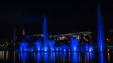 Geceleyin bir nehirde çok renkli bir müzik çeşmesi. Aydınlanmadan kaynaklanan gece çeşmesi. Mesaj için yer var. Kutlama konsepti.