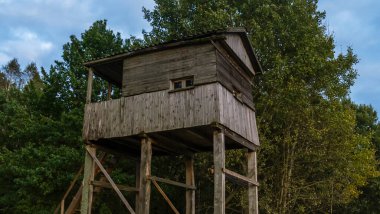Gün batımında ormanda avlanmak için bir atış ve gözlem kulesi. Ormanda ve çayırda avlanmak için tahta gözetleme kulesi..
