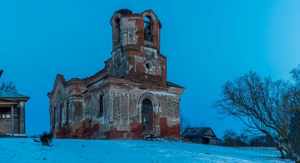 夕暮れ時の雪の中で古い教会の遺跡や近代的な木製の礼拝堂のパノラマビュー — ストック写真