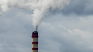 Gökyüzü arka planında bacadan çıkan endüstriyel duman. Kömür santralinden çıkan gri dumanlı yüksek baca borularının görüntüsü. Fosil yakıtla elektrik üretimi.