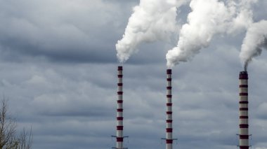 Gökyüzü arka planında bacadan çıkan endüstriyel duman. Kömür santralinden çıkan gri dumanlı yüksek baca borularının görüntüsü. Fosil yakıtlı elektrik üretimi. Rüzgâr kirliliği.