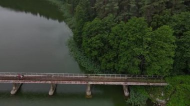 Dar göstergeli demiryolu ile köprünün yukarıdan aşağı görüntüsü. İnsanlar demiryolu tramvayında suyun üzerinde seyahat ediyorlar. Macera konsepti.