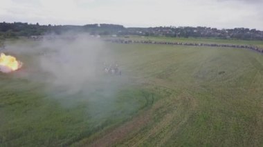 1812 savaşının yeniden inşasına dair geniş bir bakış açısı. Rus ordusu Mir Kalesi yakınlarında Fransızlara saldırıyor. Askerler topları ve tüfekleri ateşler, süvariler dörtnala koşar. Savaş meydanında patlamalar ve kurşunlar. At dövüşü..