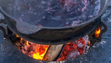 Büyük bir kazanda şarap kaynattım. Sıcak şarap büyük bir tencerede pişirilir. Geleneksel festivalde vitaminler. Çeşitli meyve ve baharatlarla sıcak şarap.
