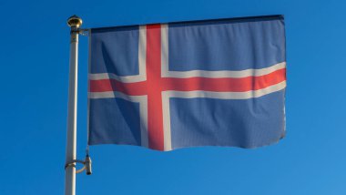 İzlanda bayrağı mavi gökyüzü arka planında. Gökyüzüne karşı rüzgarda dalgalanan İzlanda bayrağı. Diplomasi konsepti. Uluslararası ilişkiler. Metin için boşluk.