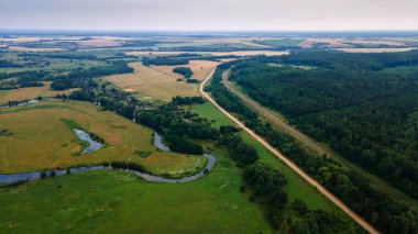 Yeşil tarladaki kıvrımlı nehrin havadan manzarası, insansız hava aracının güzel doğa arka planının üst görüntüsü. Kopya alanı olan mevsimlik yaz manzarası.