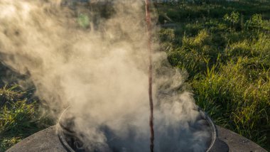 Kamp sobası ve buhar güneşli bir günde kamp macerası sırasında mavi gökyüzü ile kaseden çıkıyor. Açık hava yemekleri, turizm, seyahat, kamp konsepti..