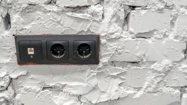Siyah elektrik prizli beyaz tuğla duvar.