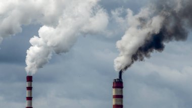 Gökyüzü arka planında bacadan çıkan endüstriyel duman. Kömür santralinden çıkan gri dumanlı yüksek baca borularının görüntüsü. Fosil yakıtla elektrik üretimi.
