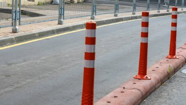 Kırmızı ve beyaz sıra trafik bariyeri yolda. Asfalt yolda yansıtıcı pigmentle plastik sütunlardan yapılmış bir bariyer. Tehlike kavramı. Trafik güvenliğini sağlamak için zıt şeritleri ayıran sütunlar.
