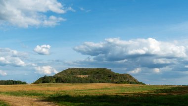 Kapalı şehir çöplüğü. Bölgenin restorasyonu. Büyük bir çöp yığınının peyzajı. Arka planda bir metropol ve bulutlu mavi bir gökyüzü var. Ekolojik sorun.