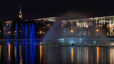 Geceleyin bir nehirde çok renkli bir müzik çeşmesi. Aydınlanmadan kaynaklanan gece çeşmesi. Mesaj için yer var. Kutlama konsepti.