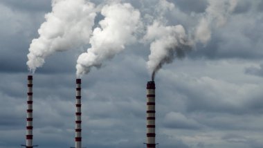Gökyüzü arka planında bacadan çıkan endüstriyel duman. Kömür santralinden çıkan gri dumanlı yüksek baca borularının görüntüsü. Fosil yakıtlı elektrik üretimi. Rüzgâr kirliliği.