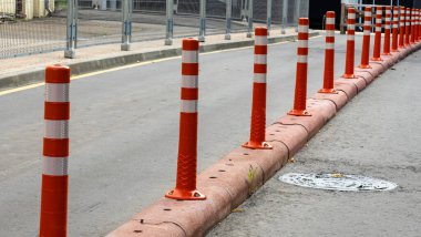 Kırmızı ve beyaz sıra trafik bariyeri yolda. Asfalt yolda yansıtıcı pigmentle plastik sütunlardan yapılmış bir bariyer. Tehlike kavramı. Trafik güvenliğini sağlamak için zıt şeritleri ayıran sütunlar.