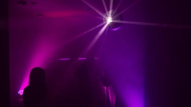 Disko gece kulübünde DJ 'in sahnede yaptığı müzikle dans eden insanların silueti. Disko topuyla parti atmosferi. Gece hayatı konsepti. Metin için boşluk.