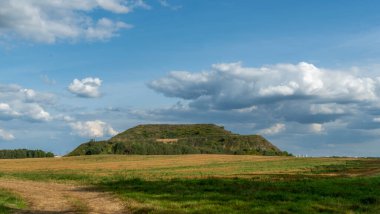 Kapalı şehir çöplüğü. Bölgenin restorasyonu. Büyük bir çöp yığınının peyzajı. Arka planda bir metropol ve bulutlu mavi bir gökyüzü var. Ekolojik sorun.