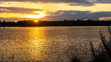 Göldeki şafak güneşinin ışınları. Nehirdeki günbatımı bulutlarının yansıması. Kırsal alan. Panoramik pankart. Doğa konsepti.