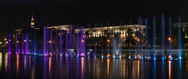 Geceleyin bir nehirde çok renkli bir müzik çeşmesi. Aydınlanmadan kaynaklanan gece çeşmesi. Mesaj için yer var. Kutlama konsepti.