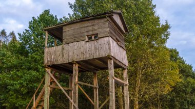 Gün batımında ormanda avlanmak için bir atış ve gözlem kulesi. Ormanda ve çayırda avlanmak için tahta gözetleme kulesi..