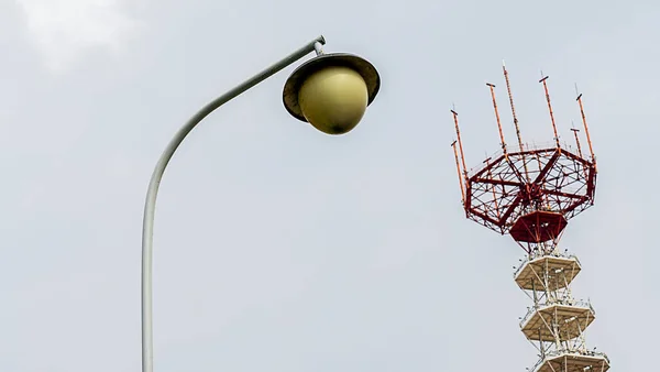 电视塔以街灯为前景色 戏剧化天空背景下的灯笼和高金属塔 — 图库照片