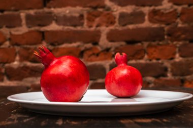 İki meyve sulu İspanyol nar porselen tabakta kırmızı tuğladan bir arka planda. Sağlıklı yaşam kavramları.