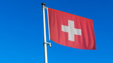 İsviçre bayrağı mavi gökyüzünün önündeki bayrak direğinde güneş ışınları ve mercek ışığı ile. Diplomasi konsepti. Uluslararası ilişkiler. Metin için boşluk.