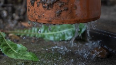 Boru hattından akan yağmur damlalarının yakın görüntüsü. Çatıdan güçlü bir su akışı bir borudan geçer. Yağmur kavramları. Tasarım için resim. Metin için boşluk.
