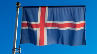 İzlanda bayrağı mavi gökyüzü arka planında. Gökyüzüne karşı rüzgarda dalgalanan İzlanda bayrağı. Diplomasi konsepti. Uluslararası ilişkiler. Metin için boşluk.